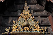 Chiang Mai - The Wat Phan Tao temple, detail of the entrance of the Wihan with the image of a peacock standing over a sleeping dog. 